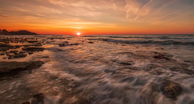 Stunning sunrise over the sea with motion blur waves