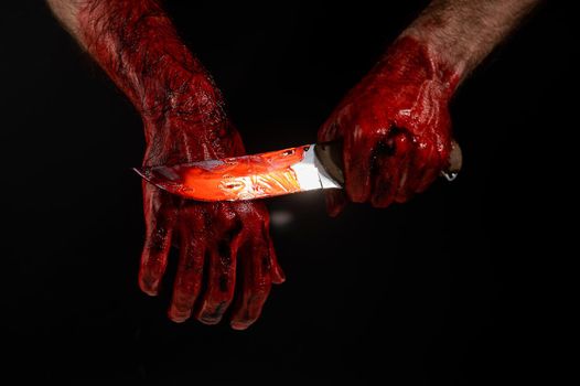 Man holding knife with bloody hand on black background