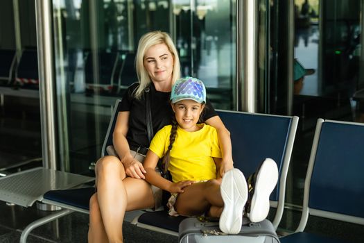 happy mother and daughter at airport travelling together.