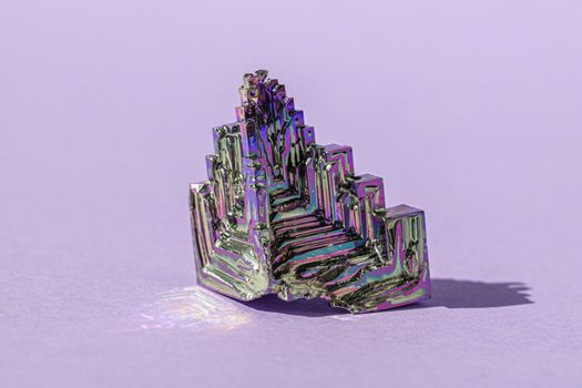 Synthetic bismuth Bismuthum crystal with iridescent oxide film on pink background close up isolated. Amazing colorful shiny rainbow Bismuth Gemstone mineral. Banner