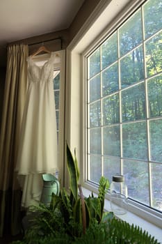 Beautiful White Wedding Dress Hanging in Window of Country House. High quality photo