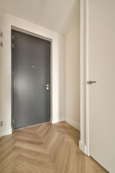 A narrow corridor with parquet floor leading inside a cozy house in white