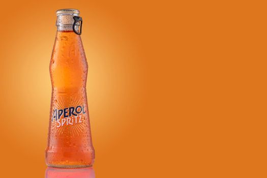 Bottle of Aperol Spritz summer cocktail drink on orange background.