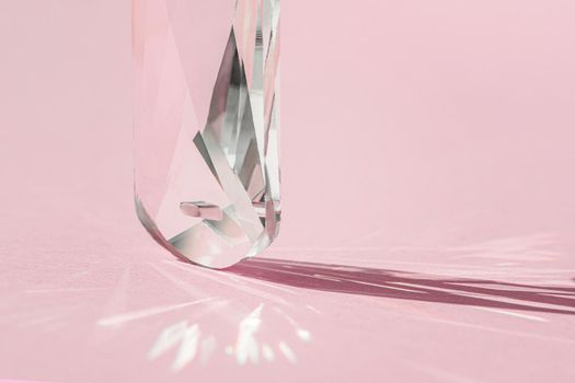 Crystal prism with light diffraction of spectrum colours and reflection with trendy light and hard shadows on pink background. Light spectrum reflected through glass prism. Banner