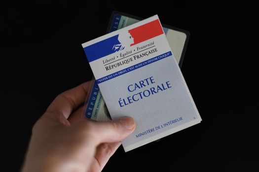 PARIS, FRANCE - MARCH 09, 2020: Hand holds a french electoral card and an identification card for voting