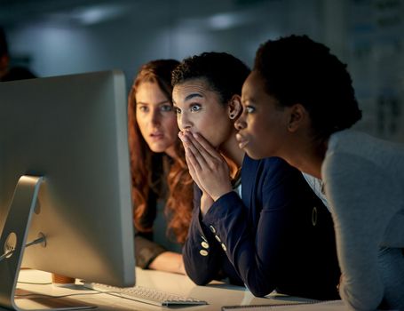 Cropped shot of a group of colleagues looking shocked while working late in an office.