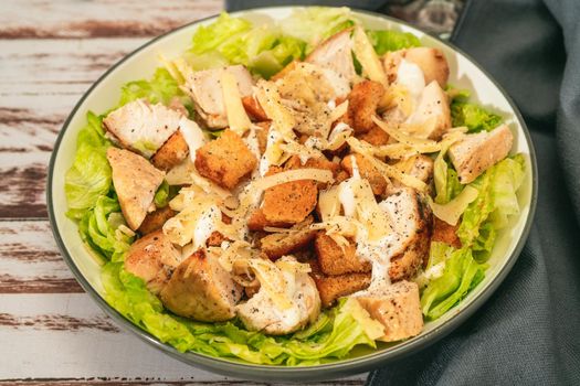 Exquisite Caesar salad with small bites of chicken and a traditional aioli sauce in a small bowl on a rustic table. High view. gourmet concept, Natural food.