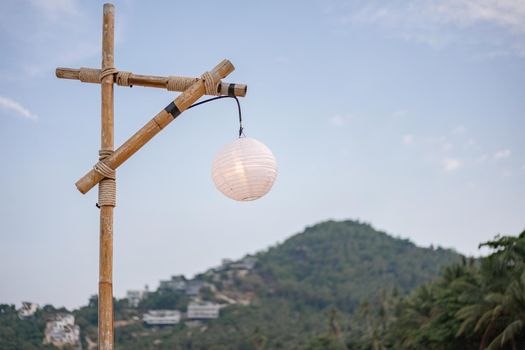 Bamboo pole and white lamp with blue sky and green mountain.