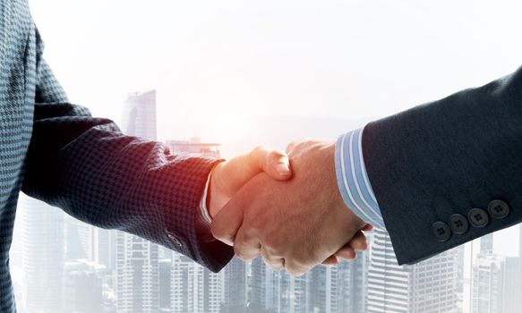 Close-up of the handshake of businessmen. Against the backdrop of the cityscape