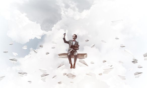 Funny man in red glasses and suit sitting on book and paper planes flying around