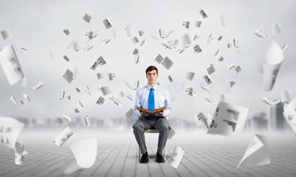 young businessman with book on office chair