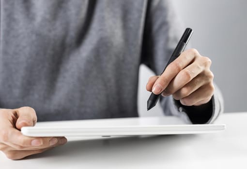 Close-up of female hands touching screen of digital tablet. Businesswoman sitting at desk and working at tablet computer. Consultant at workplace in office. Business and digital technology concept.