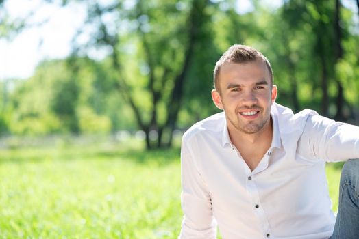 Portrait of a young man in the park. Smiling and happy