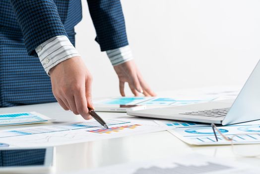 Businesswoman standing near office desk with laptop and documents. Financial audit and consulting. Corporate manager in suit working with online business analytics. Investment and stock trading