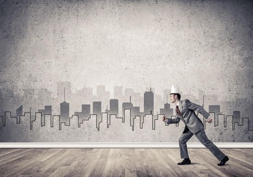 Young handsome businessman wearing white paper crown running in a hurry