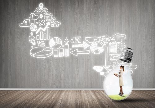 Businesswoman inside of light bulb in empty concrete room