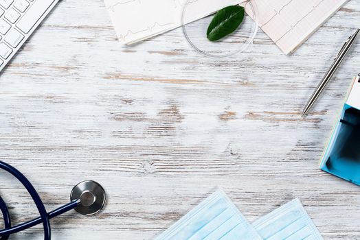 Doctors desktop with medical supplies. Computer keyboard, x-ray image, stethoscope and cardiogram lies on wooden desk. Healthcare technology concept with copy space. Medical consultation and treatment