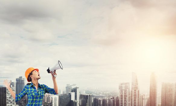 Engineer woman with megaphone on modern city landscape