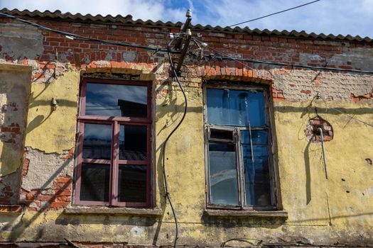 A shabby, rough, cracked wall, with windows. The concept of devastation caused by war, poverty