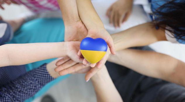 Group of people holding hearts with flag of Ukraine in their hands closeup top view. Worldwide support and assistance to Ukrainian people concept