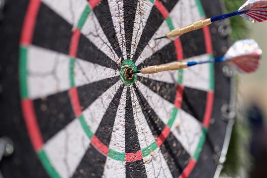 Two darts sticking out of wooden target closeup. Sports entertainment in resort concept
