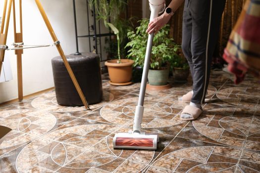 Woman housewife cleaning floor with cordless vacuum cleaner closeup. House cleaning concept