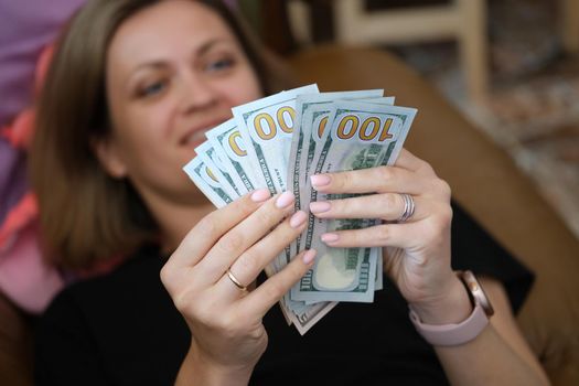 Woman lying on couch and counting bunch of dollar bills closeup. Planning budget concept