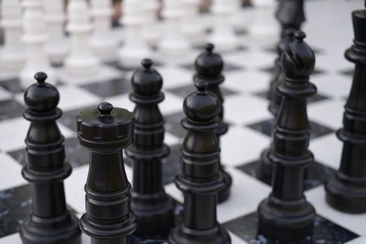 Black and white chess pieces standing on boards on street closeup. Holding chess tournaments concept