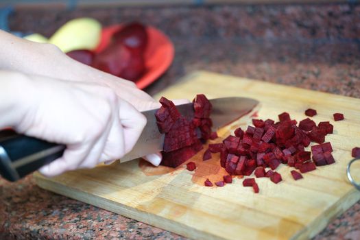 Woman housewife cutting beets into cubes for salad closeup. Healthy food vegetarian cuisine concept