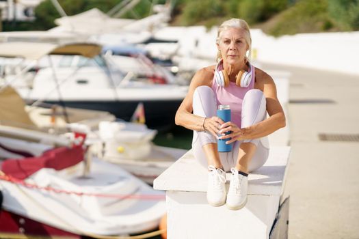 Mature sportswoman taking a break during exercise. Concept of healthy living in the elderly. Senior woman in fitness clothing. Older female doing sport to keep fit.