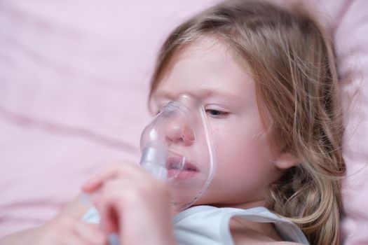 Little girl making inhalation of hormonal drug using nebulizer. Treatment for attacks of bronchial asthma and stenosing laryngitis in children concept