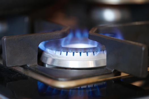 Gas burner on stove with blue fire at home closeup. Gas price regulation concept