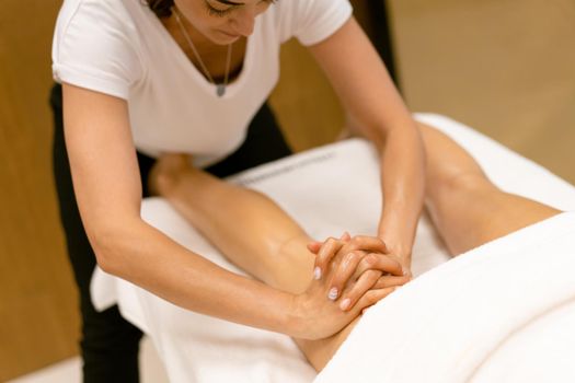 Woman receiving a leg massage with massage candle oil. Body care treatment in a beauty centre.