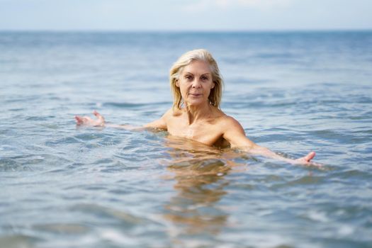 Older woman in good shape bathing in the sea. Elderly female enjoying her retirement at a seaside retreat.