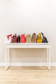 Collection of handbags standing in a row on a white table
