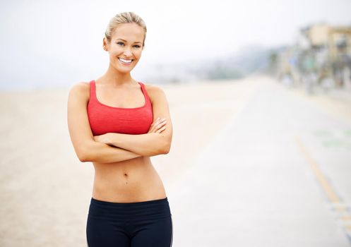 Portrait of a young woman in sportswear standing at the beach.