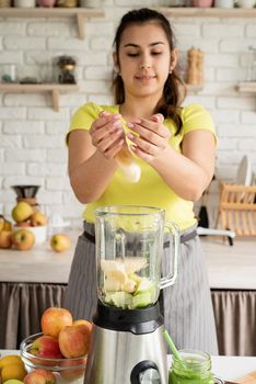 Preparing healthy foods. Healthy eating and dieting. Young brunette woman making banana smoothie at home kitchen