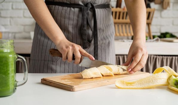 Healthy eating, dieting concept. High angle view of female hands cutting banana in the kitchen