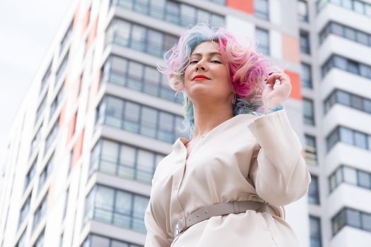 Portrait of a middle-aged woman with multi-colored hair walks on the streets of the city