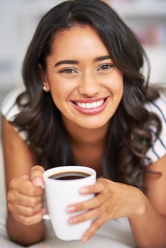 Cropped portrait of a young woman drinking coffee while relaxing on her sofa at home.