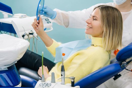 The dentist shows the client the results of his work in the mirror.