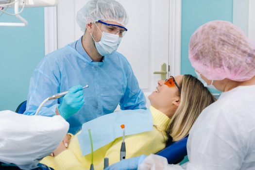 A female patient in dental glasses treats teeth at the dentist with ultraviolet light. dental fillings.