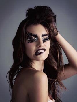 Studio shot of an attractive young woman wearing bold makeup.