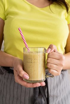 Healthy eating, dieting concept. Young brunette woman drinking fruit banana smoothie at home kitchen from mason jar