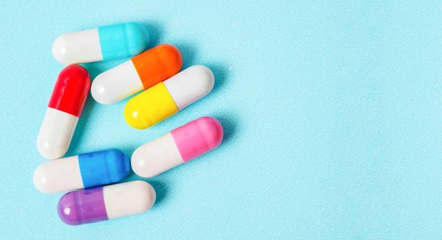 Colorful capsules (pills) on a blue background. Medical background, template.