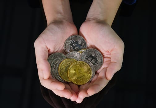 Closeup image of a women holding and giving golden color bitcoins