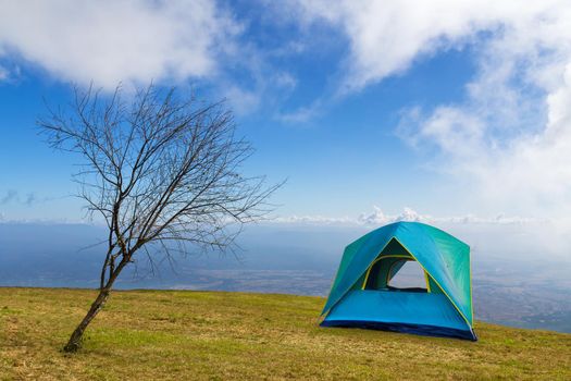 Tent camping  on a grass under white clouds and blue sky in morning time