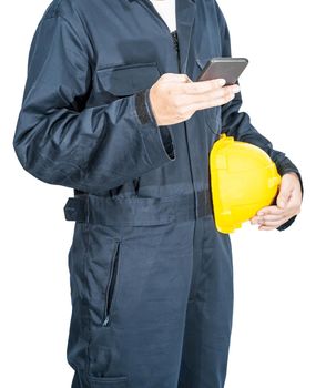 Cloes up Worker standing in blue coverall holding yellow hardhat and use smartphone isolated on white background