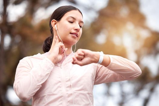 Shot of a young woman checking her pulse while exercising in nature.