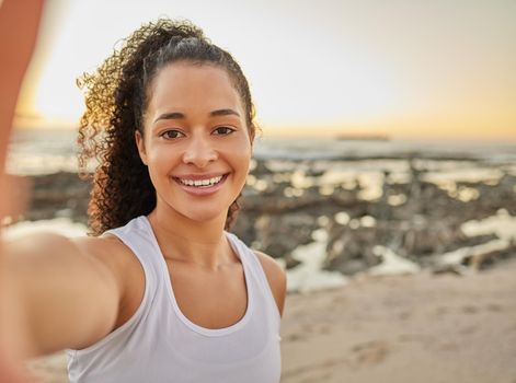 Cropped portrait of an attractive young woman taking a selfie during her workout at the beach.